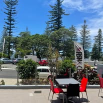 Outdoor seating with red chairs and shop flag